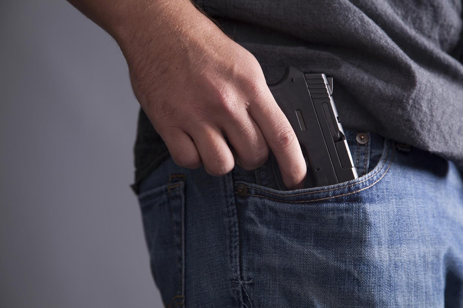 A New York gun owner sliding handgun into jeans pocket; concealed carry concept.